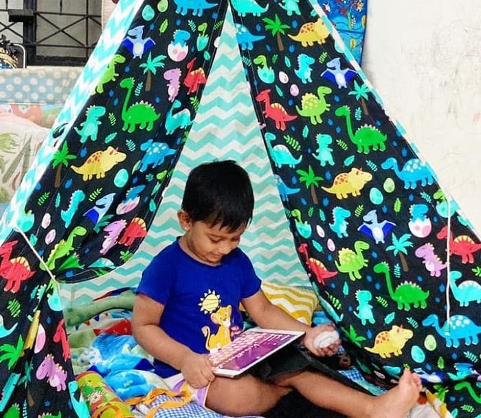 boy reading book in a dinosaur teepee tent