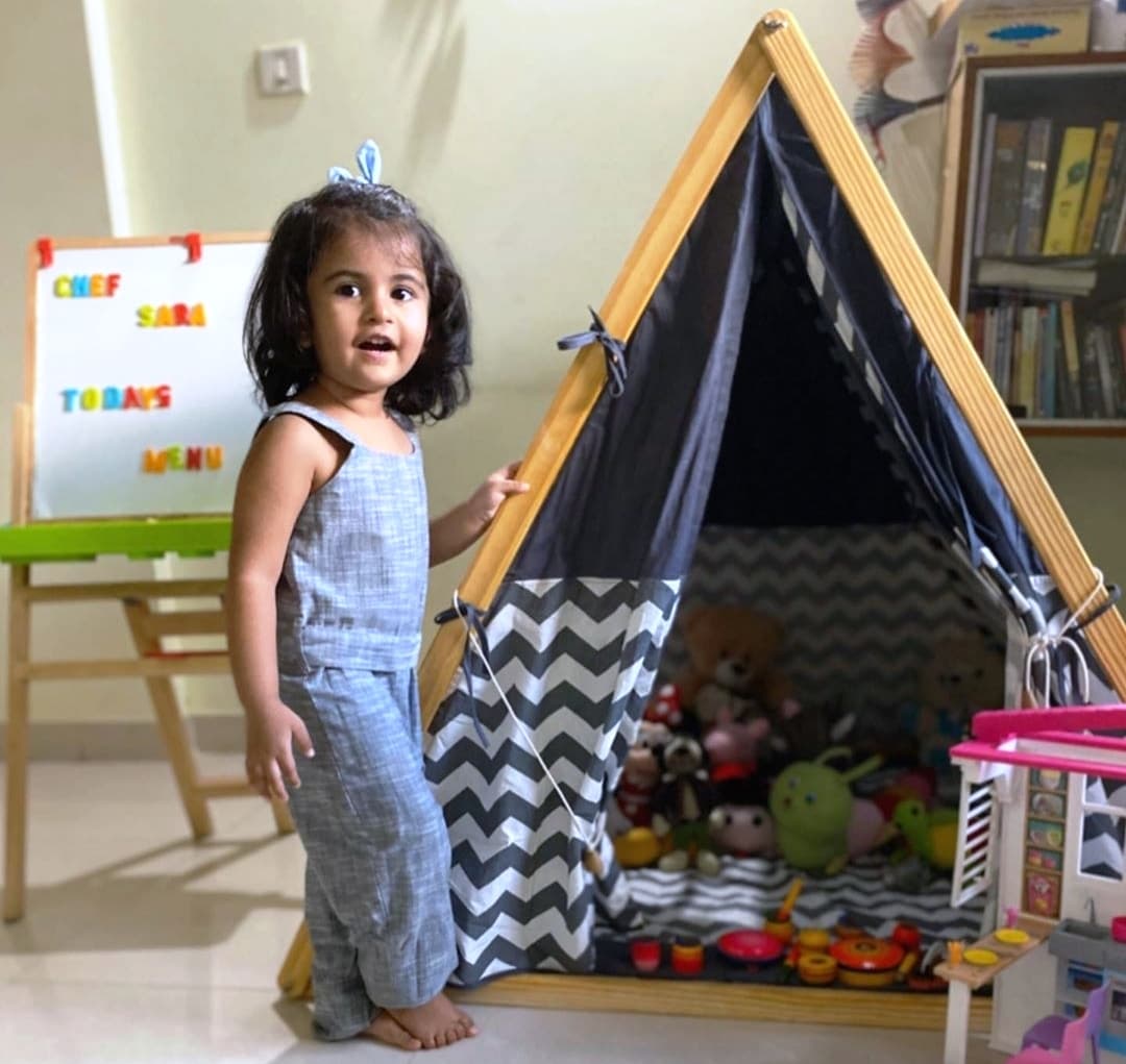 A small girl standing in front of her A-Shape kids tent in grey color