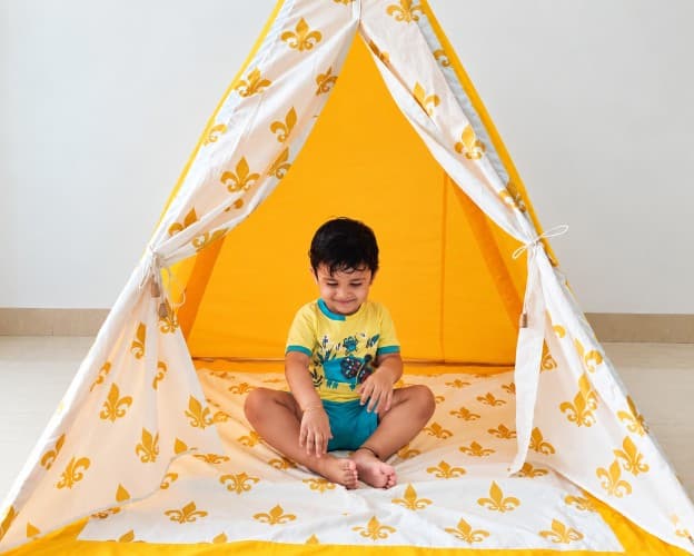 baby sitting in a yellow play tent