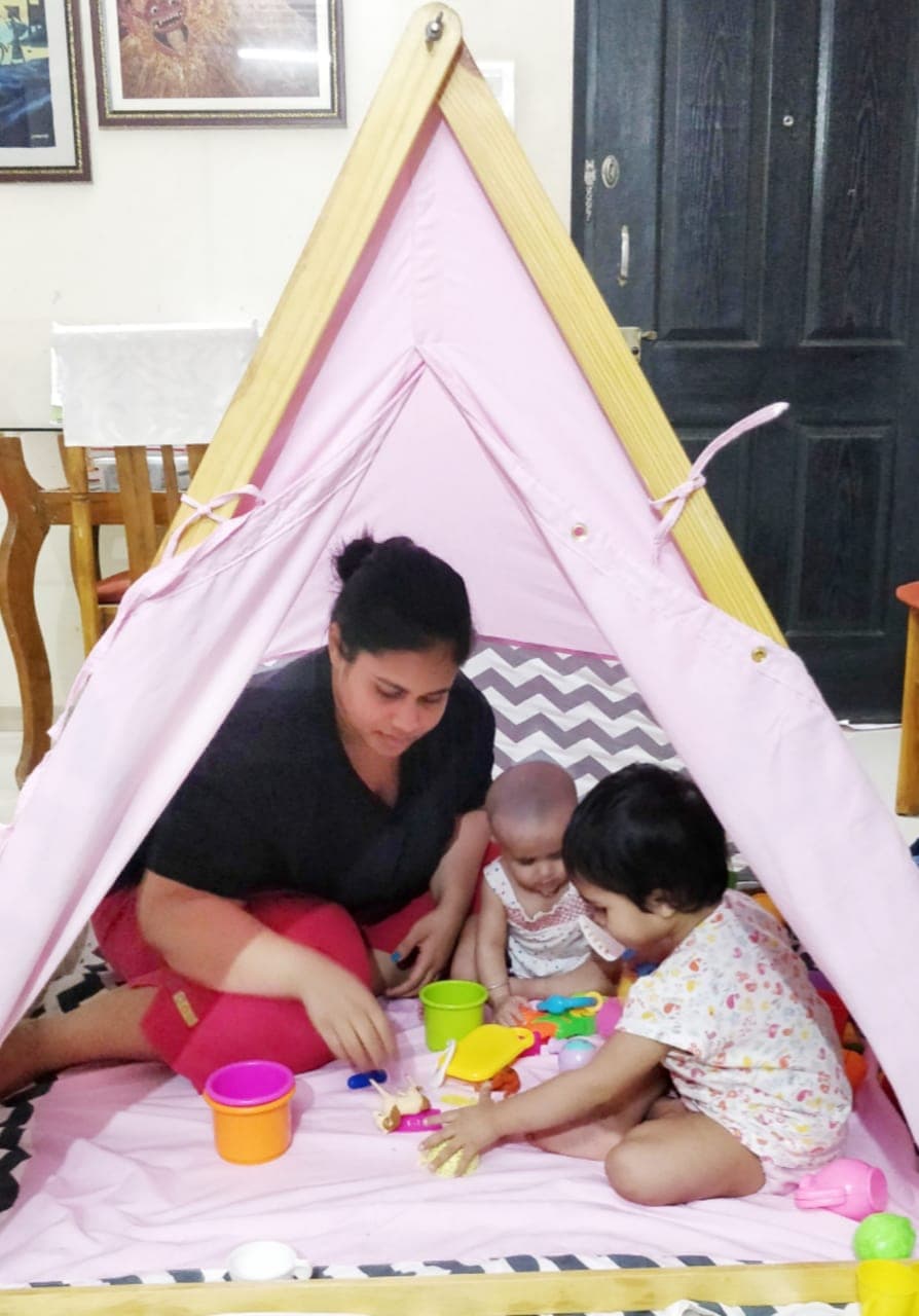 mother and daughter sitting inside a play tent reading a book