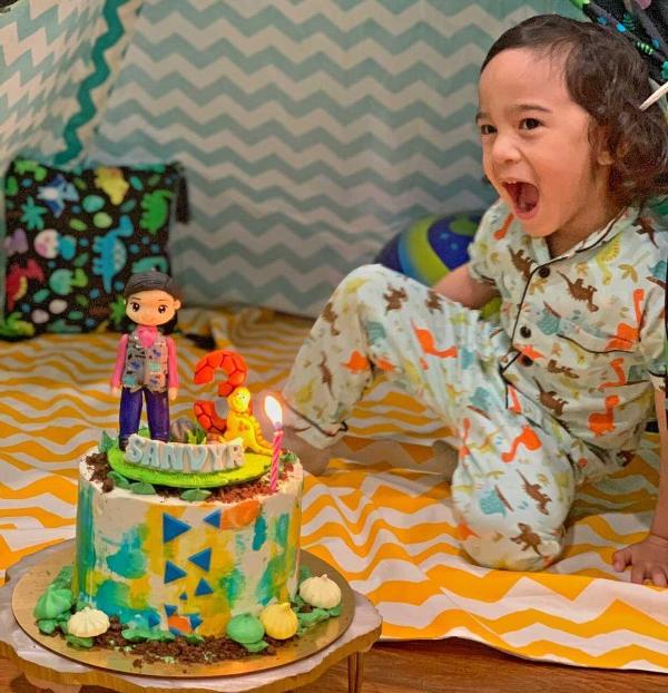 kid sitting in his play tent with his dinosaur cake