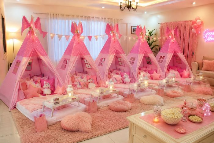 Five pink teepee tents arranged in a cozy indoor girls’ sleepover party setup, decorated with fairy lights, plush toys, soft bedding, pillows, and pink party décor.